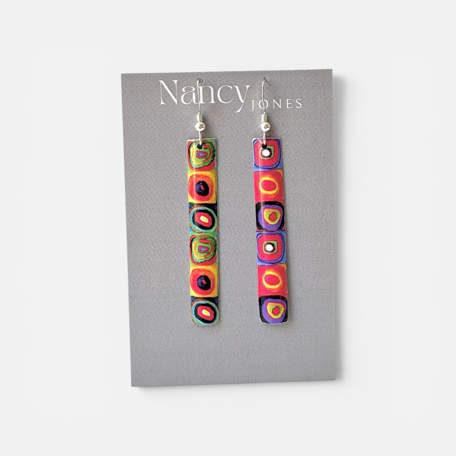 Colorful earrings on a Nancy Jones card against a white background