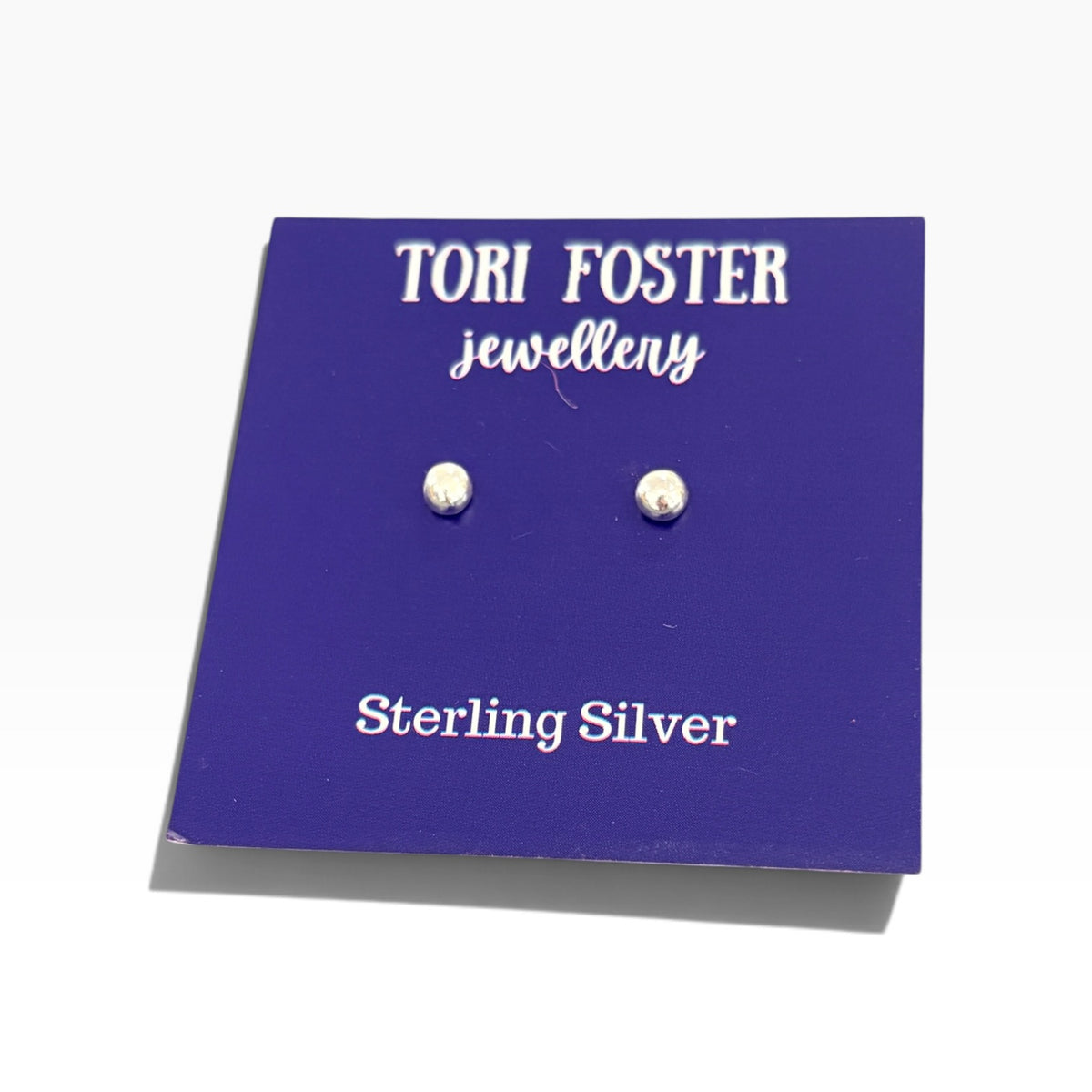 A pair of sterling silver stud earrings displayed on a purple backing card that reads &
