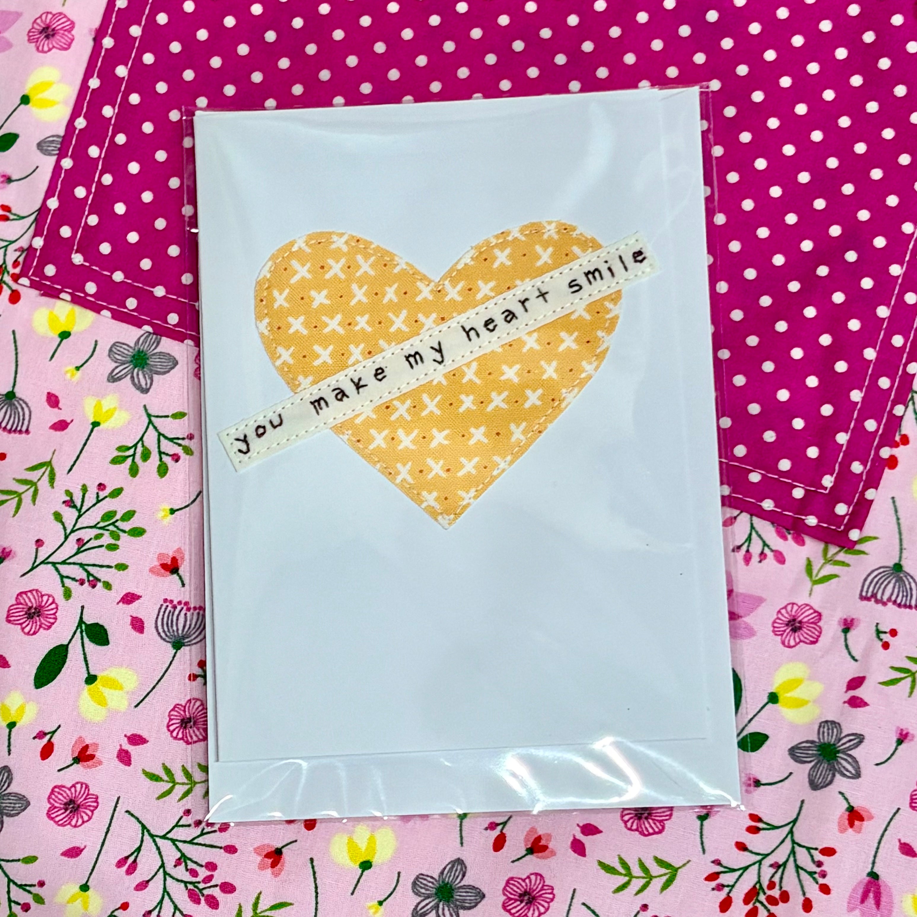 Heart-shaped card with text on a colorful fabric background