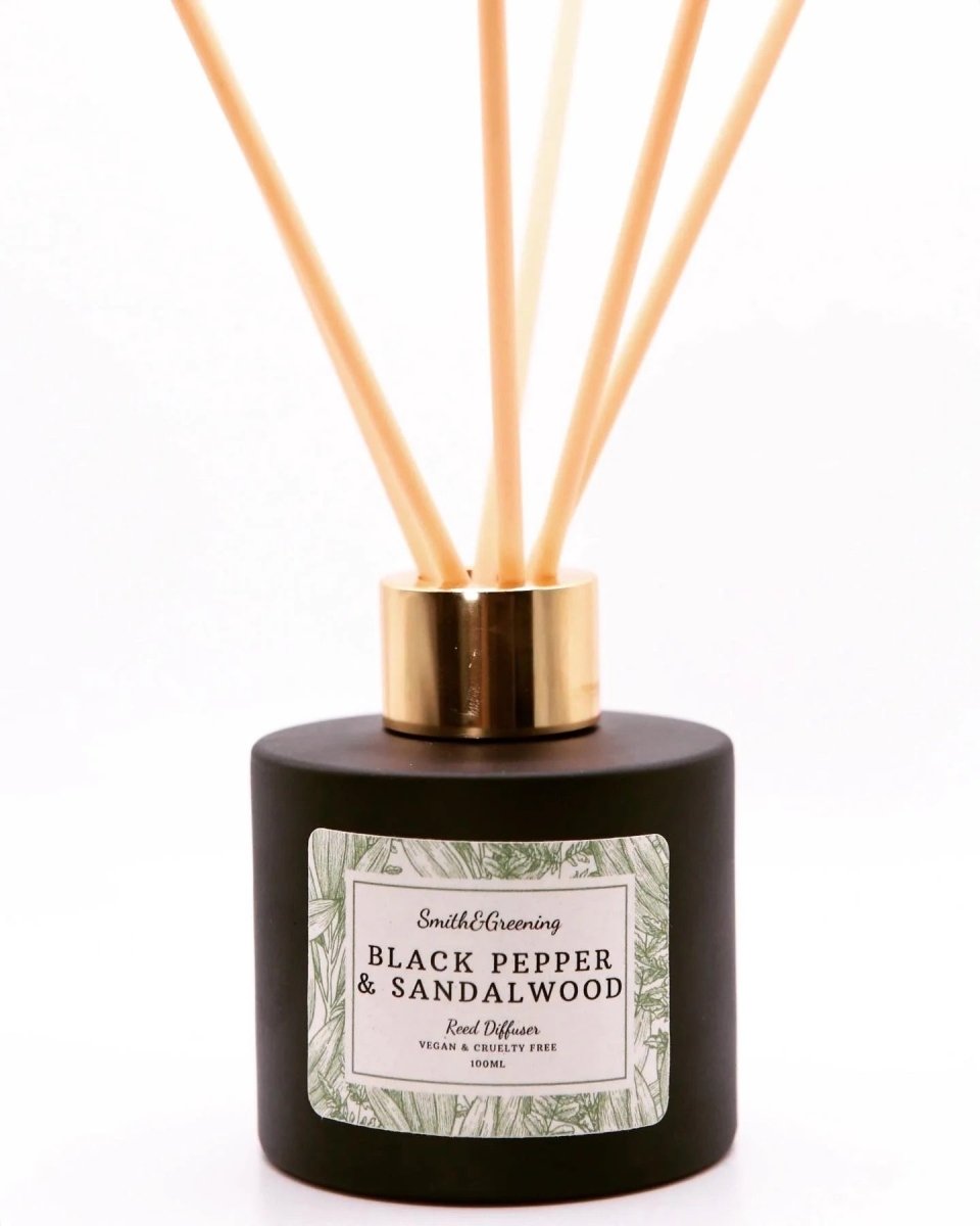 Reed diffuser with black container and gold cap on a white background