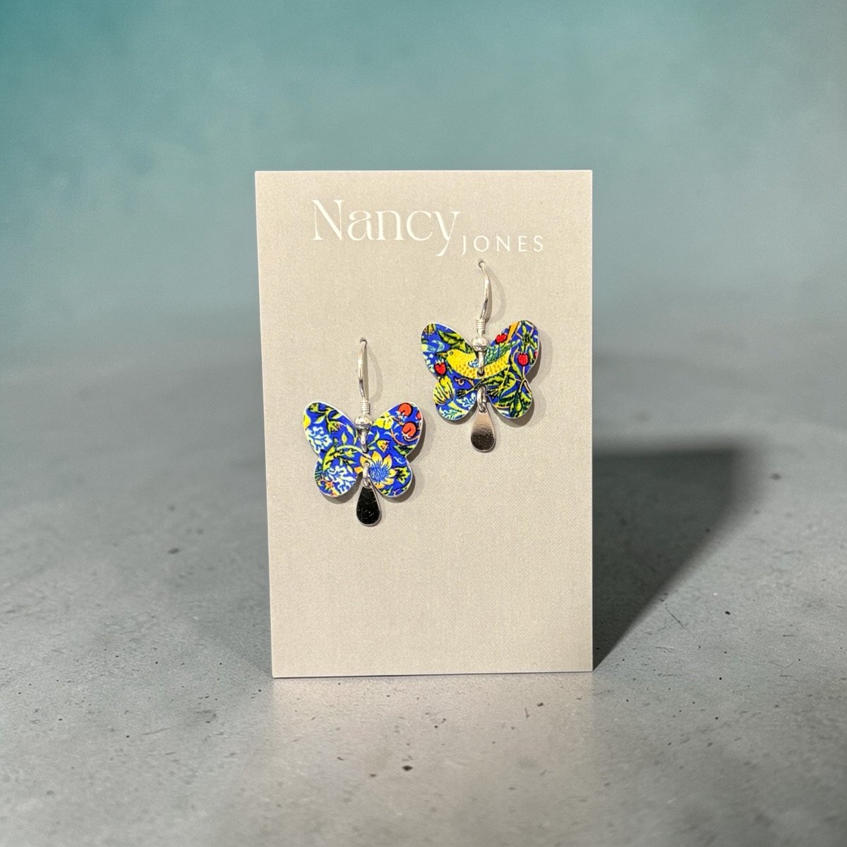 Butterfly earrings on a Nancy Jones card against a gray background