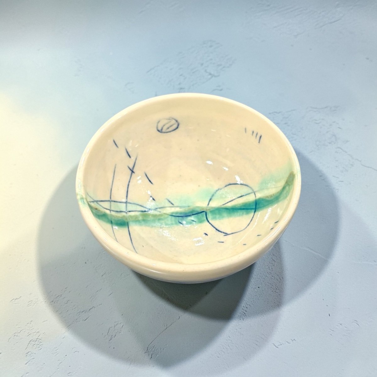 Small ceramic bowl with artistic design on a light blue background