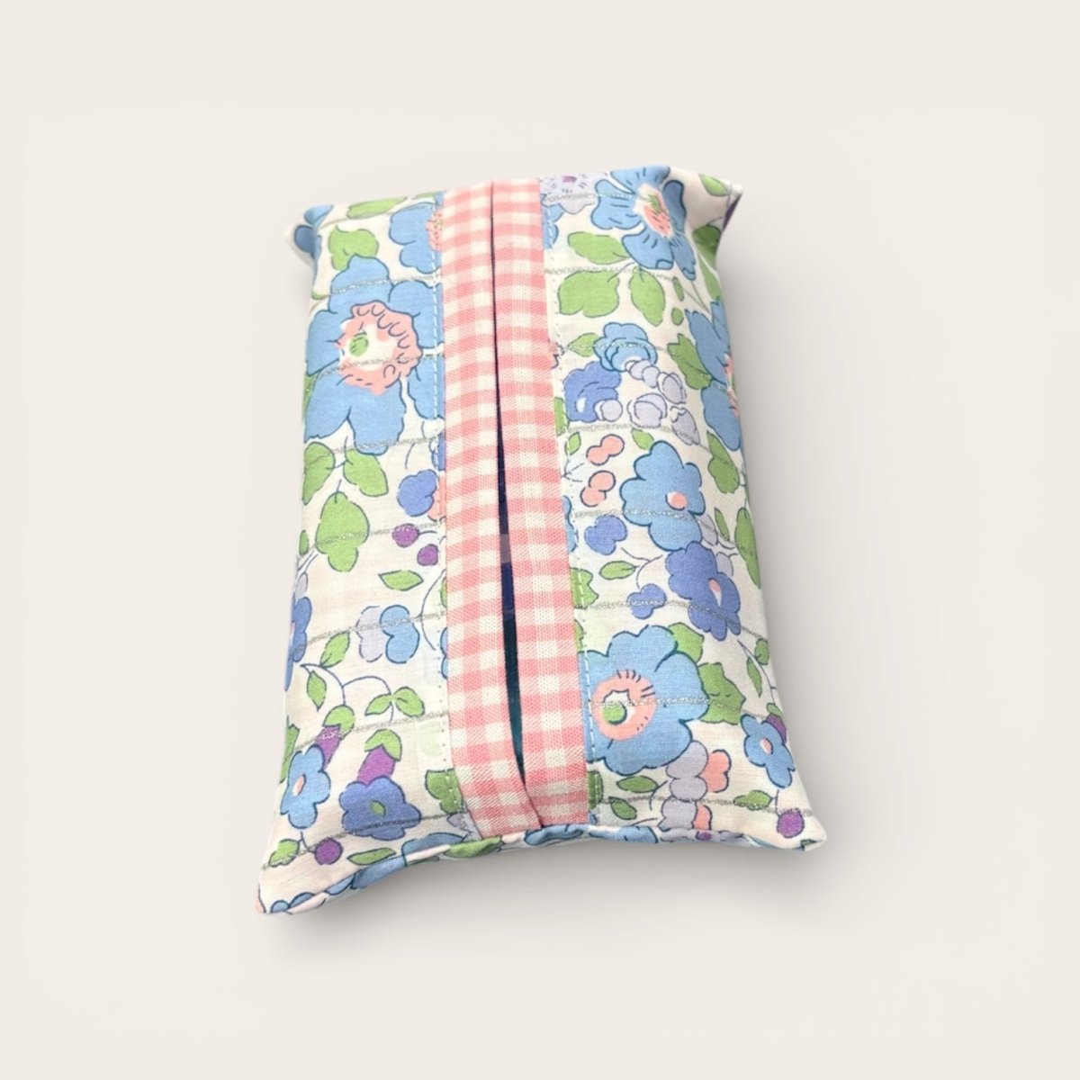 Floral-patterned tissue holder with a pink striped center on a white background