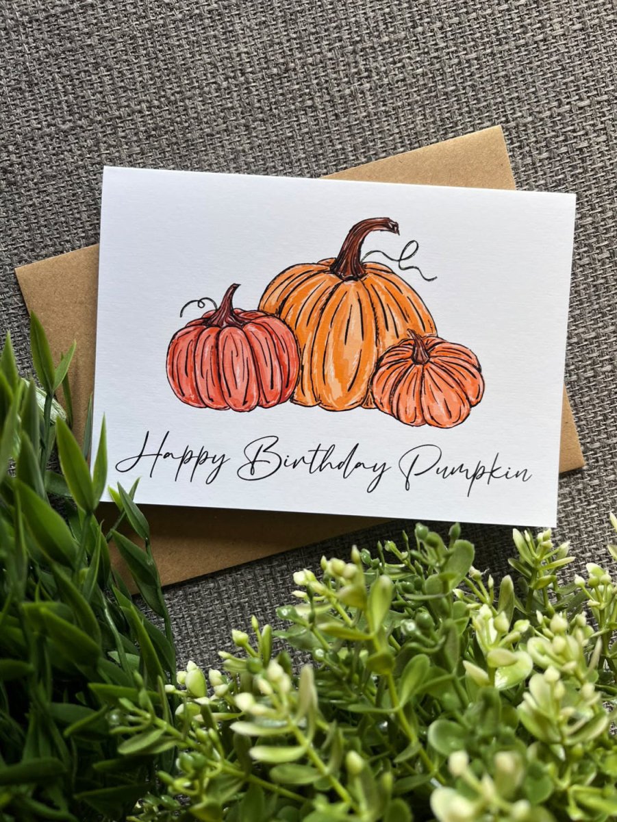 A white greeting card with an illustration of three orange pumpkins and the handwritten text &