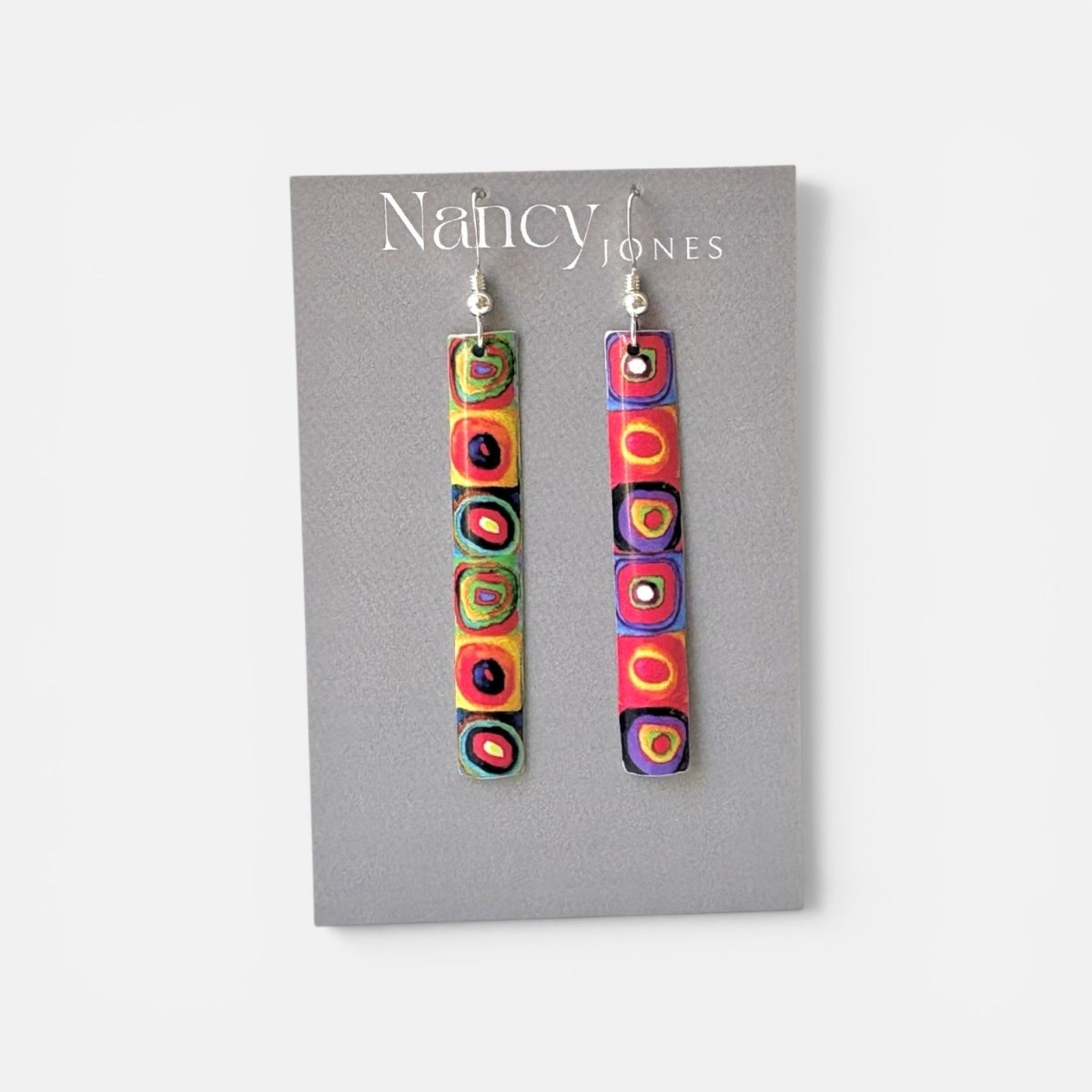 Colorful earrings on a Nancy Jones card against a white background