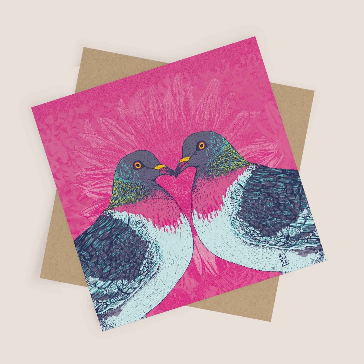 Greeting card with two birds on a pink background, placed on a beige envelope.