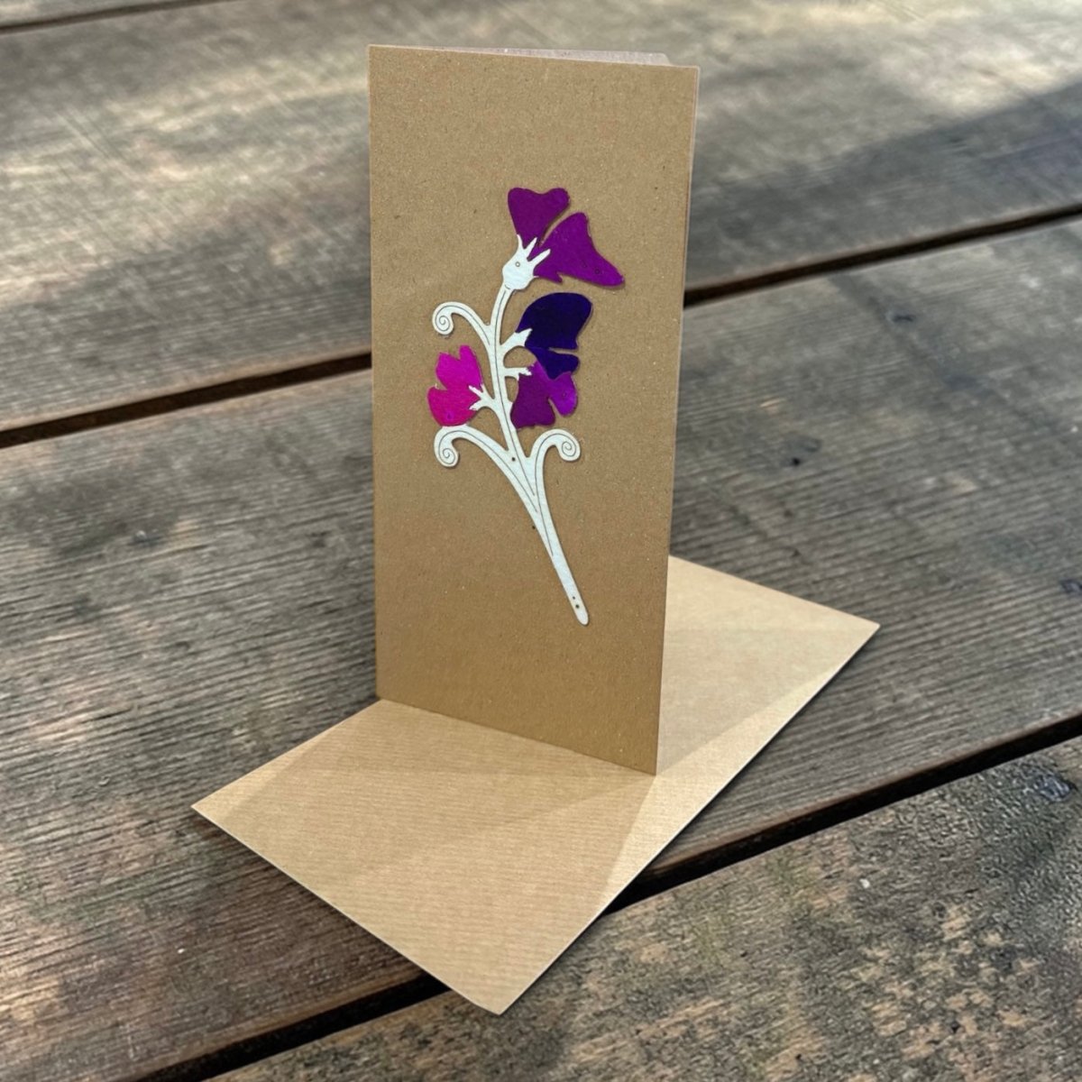 Brown greeting card with floral design on a wooden surface