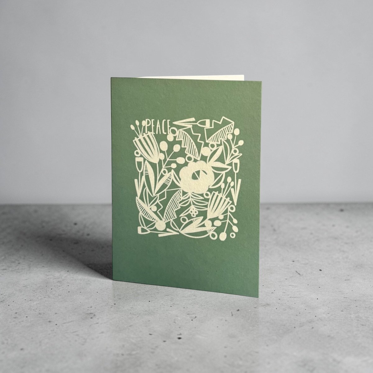 Green card with white floral design and &