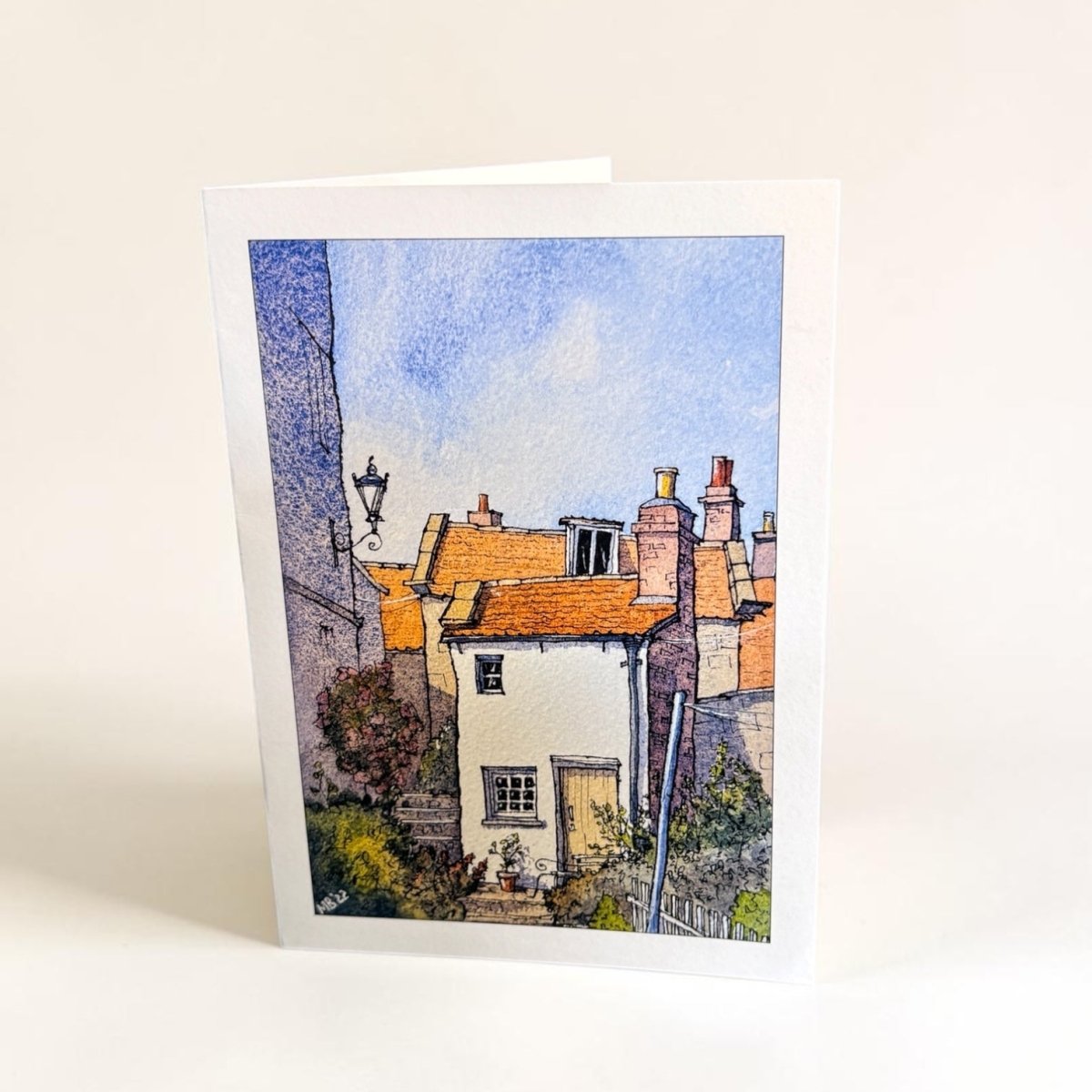 Greeting card with a painting of a quaint village scene on a white background