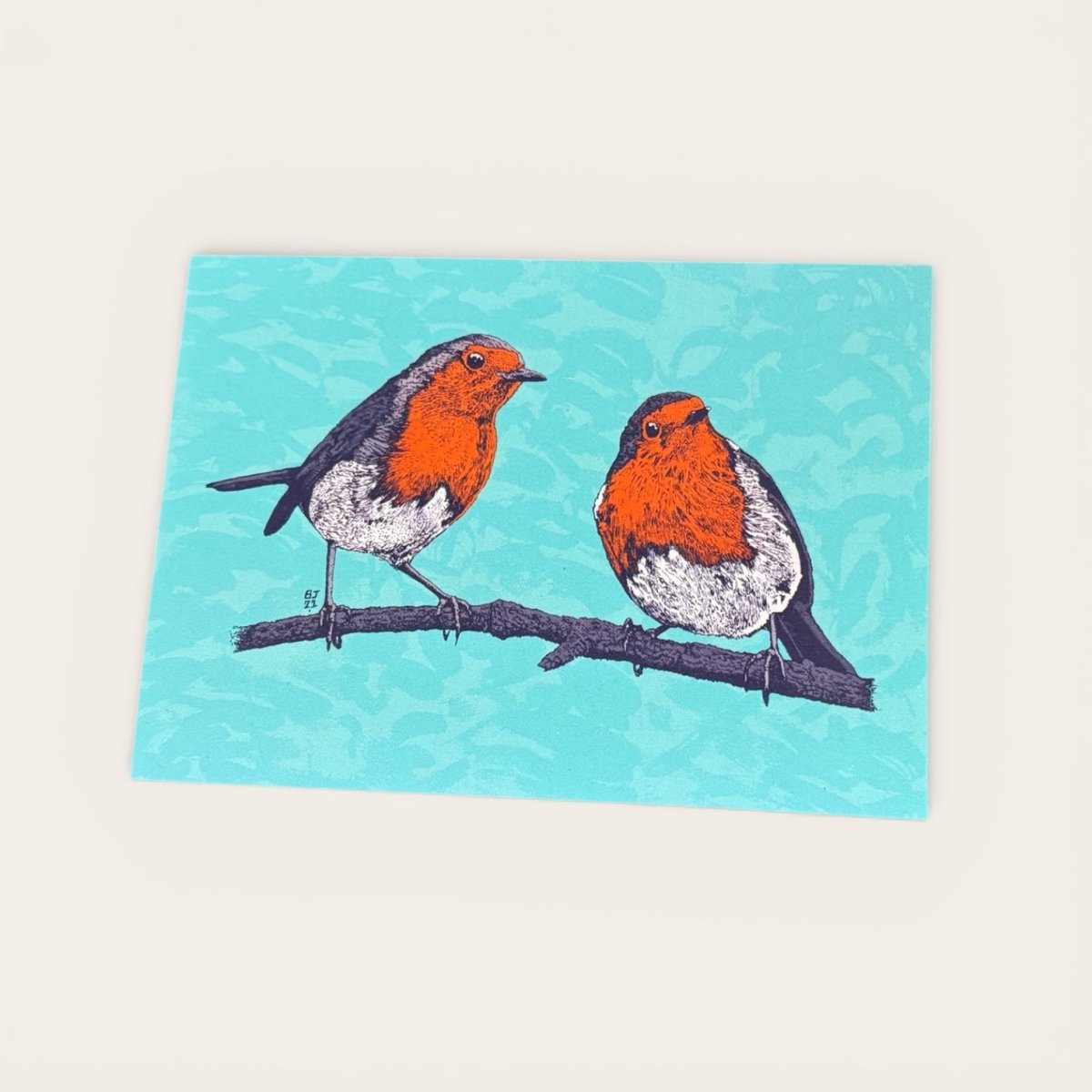 Two robins on a branch with a blue background