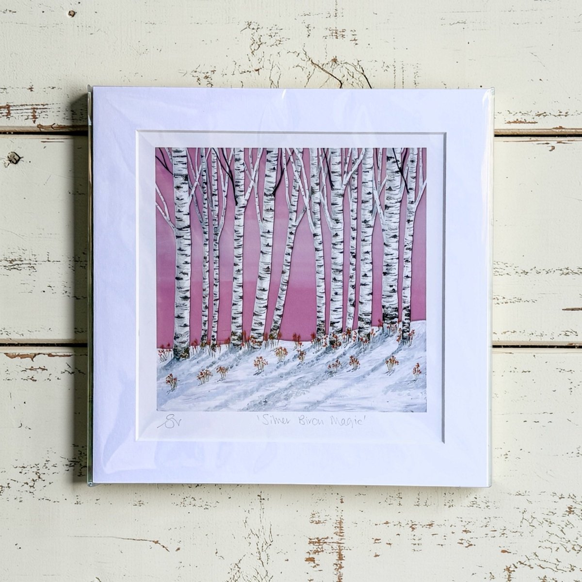 Framed artwork of a snowy landscape with birch trees on a pink background