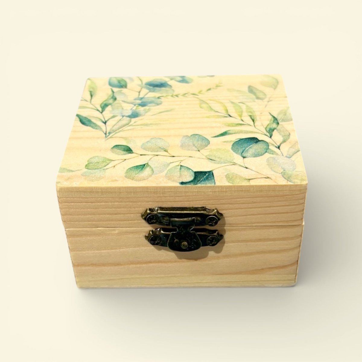 Wooden box with leaf pattern on lid against a light background