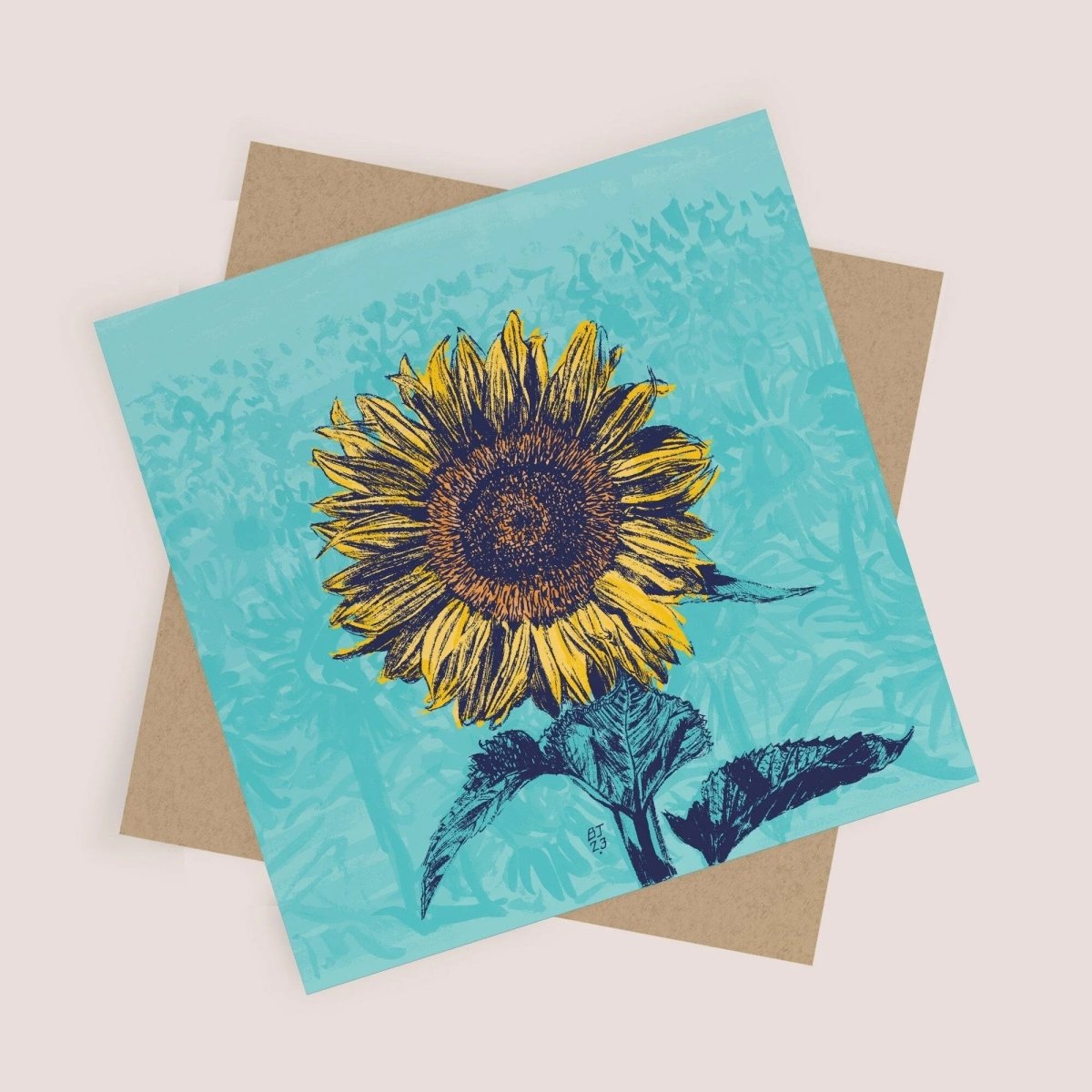 Card with a sunflower design on a turquoise background, placed on a beige envelope.
