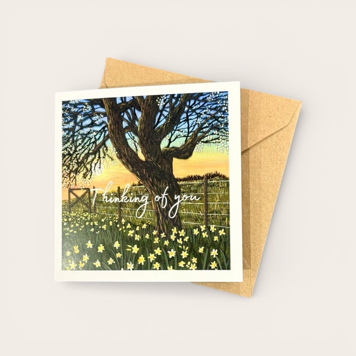 Greeting card with a tree and flowers design and a brown envelope on a light gray background