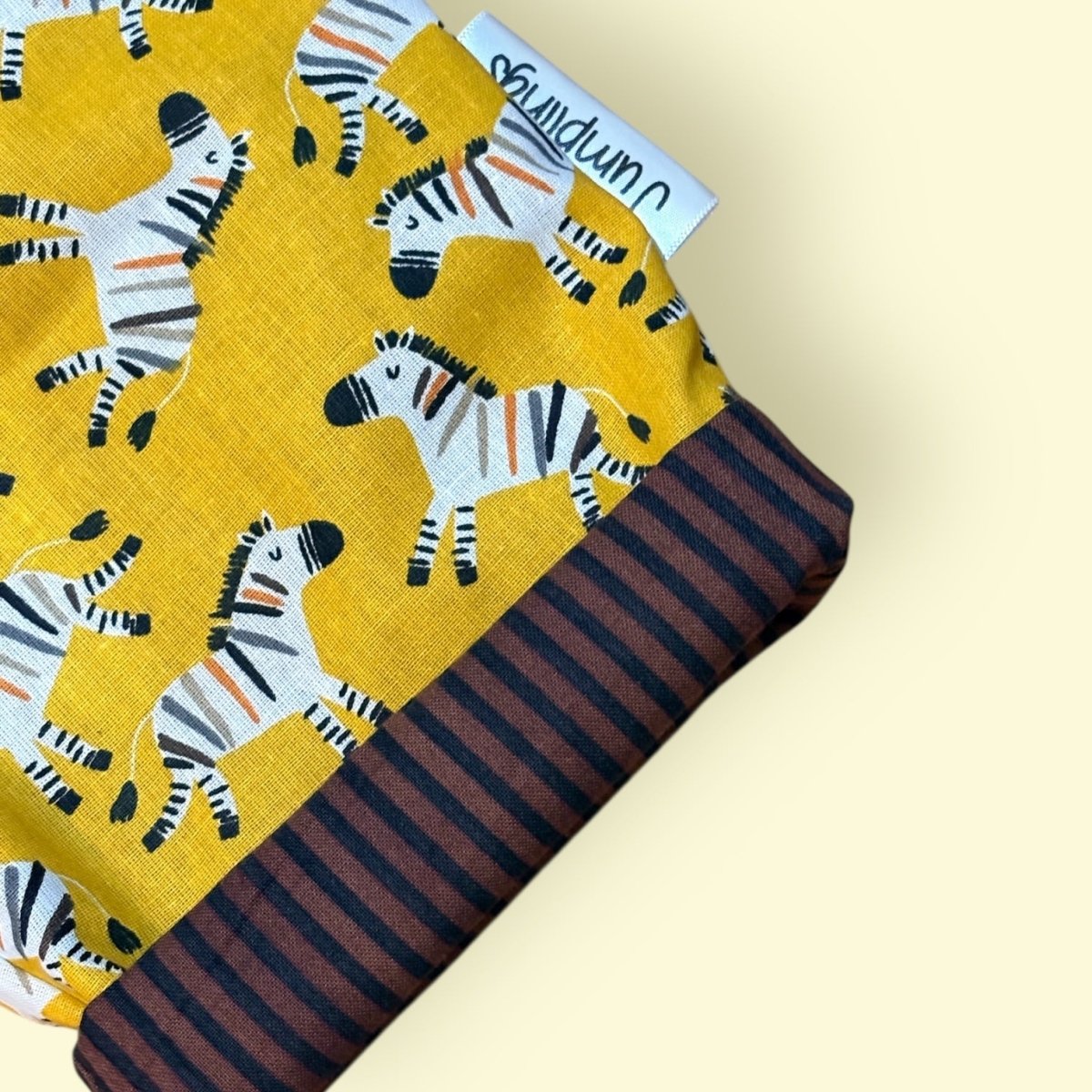 Fabric with zebra pattern on yellow background and striped brown fabric underneath
