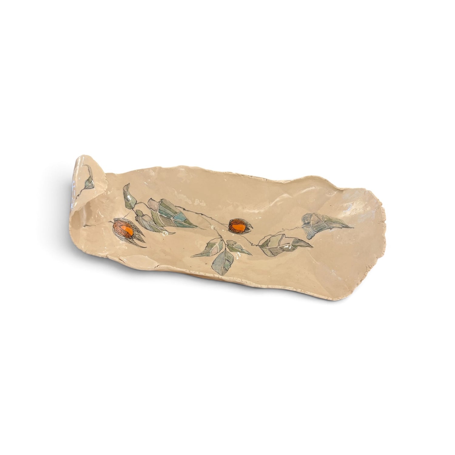 A handmade ceramic serving platter with an organic, irregular shape, featuring a hand-painted design of green leaves and small orange berries on a warm beige background.