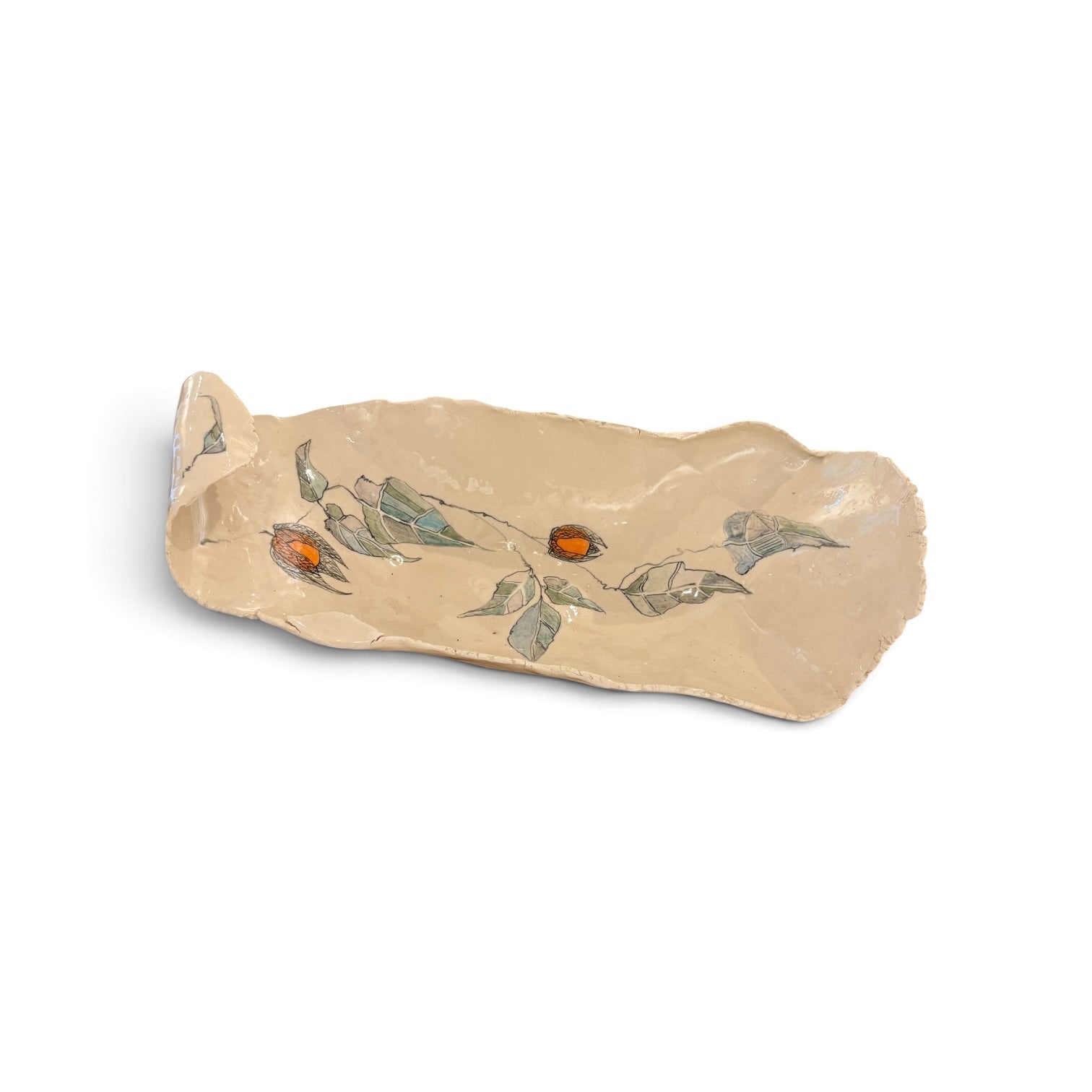 A handmade ceramic serving platter with an organic, irregular shape, featuring a hand-painted design of green leaves and small orange berries on a warm beige background.