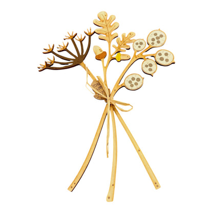 A decorative wooden botanical arrangement with three legs, featuring laser-engraved branches, leaves, acorns, and circular seed pods, tied with a simple bow on a white background.