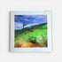 Framed painting of a landscape with a tree on a hillside.