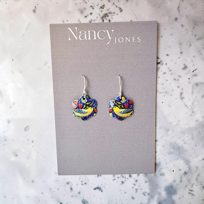 Colorful heart-shaped earrings on a Nancy Jones card against a marble background