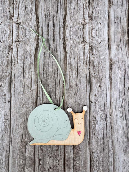Decorative snail ornament hanging on a wooden surface_Just Makers