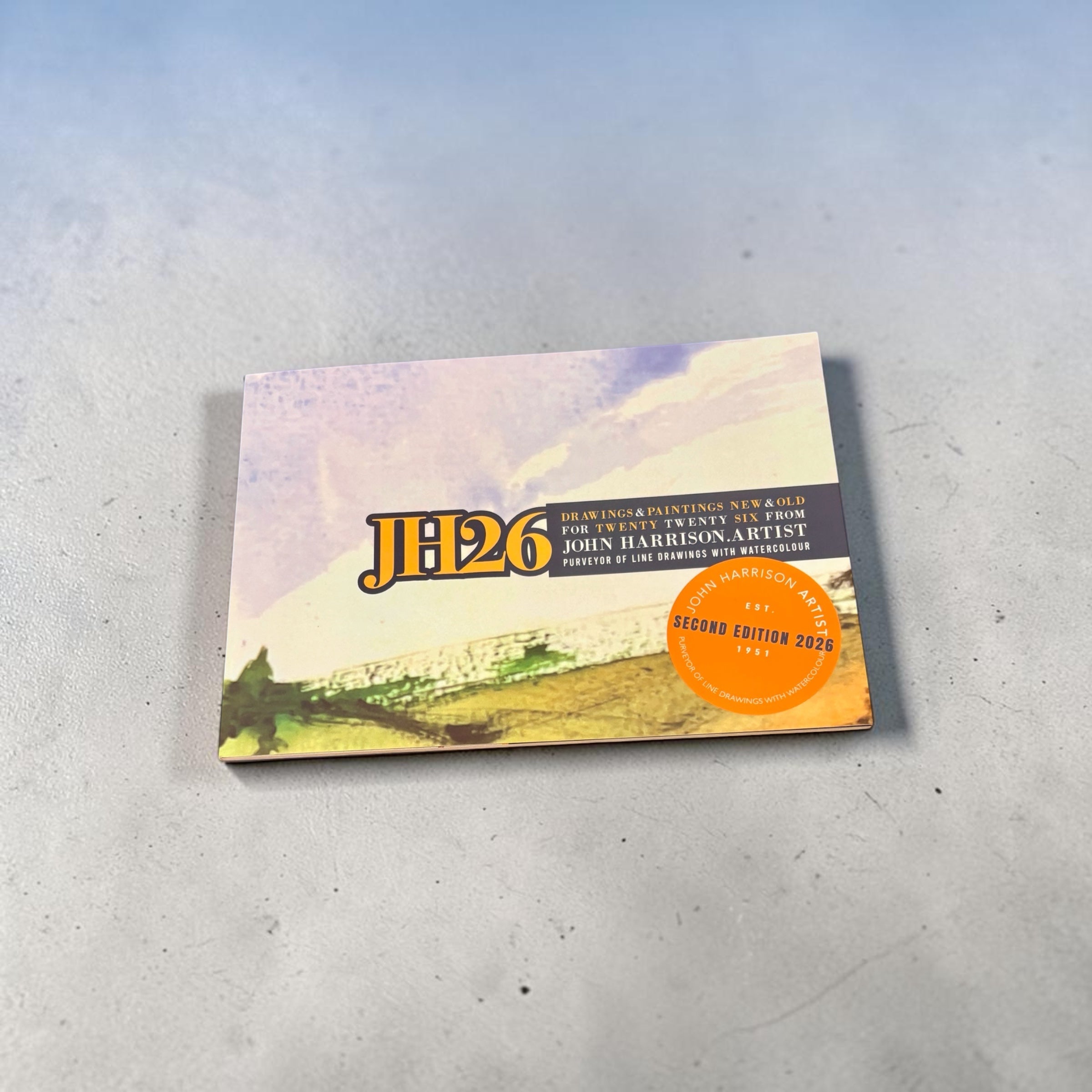 A square art print or album cover titled "JH26" by John Harrison Artist, featuring a watercolor landscape with a bright orange circular sticker reading "Second Edition 2026," photographed on a light gray surface.