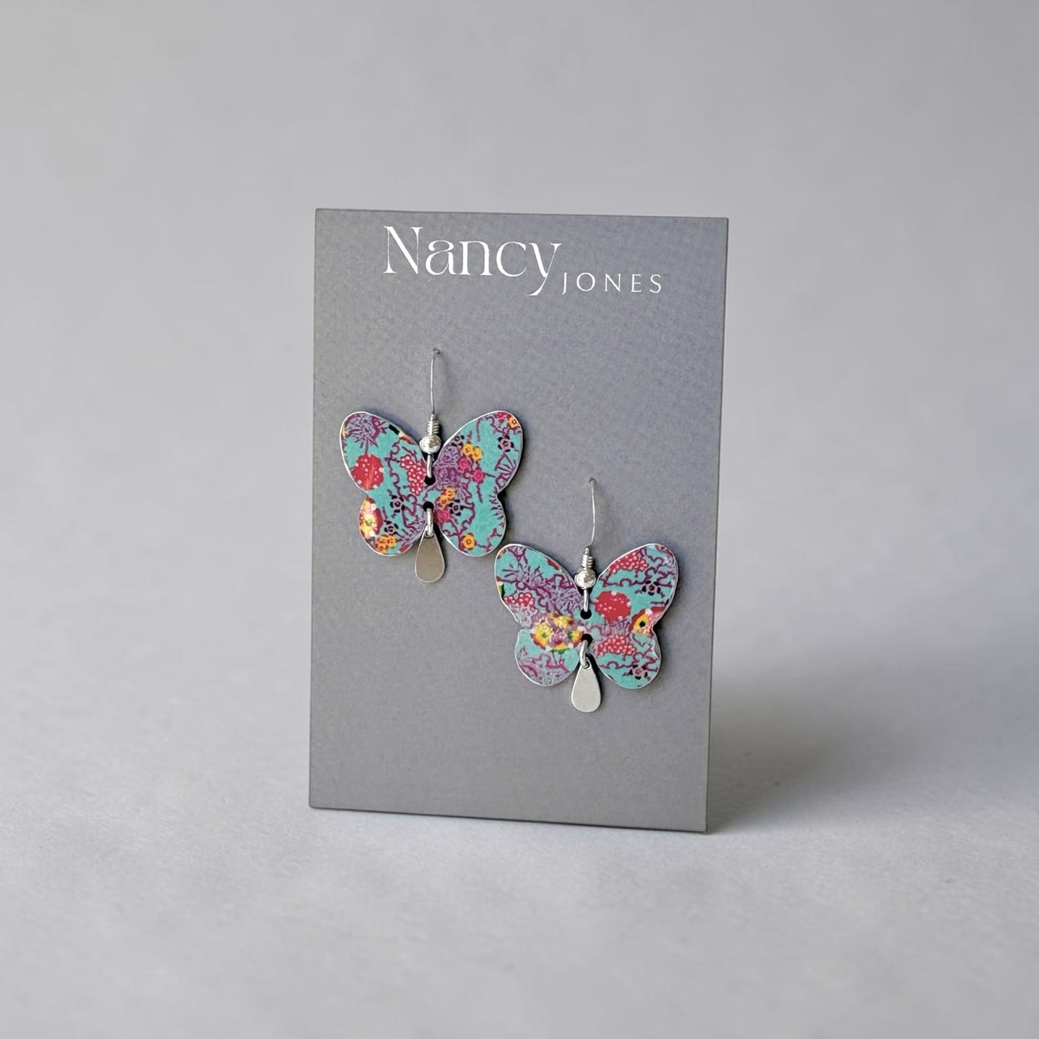 Butterfly earrings on a Nancy Jones branded card against a gray background