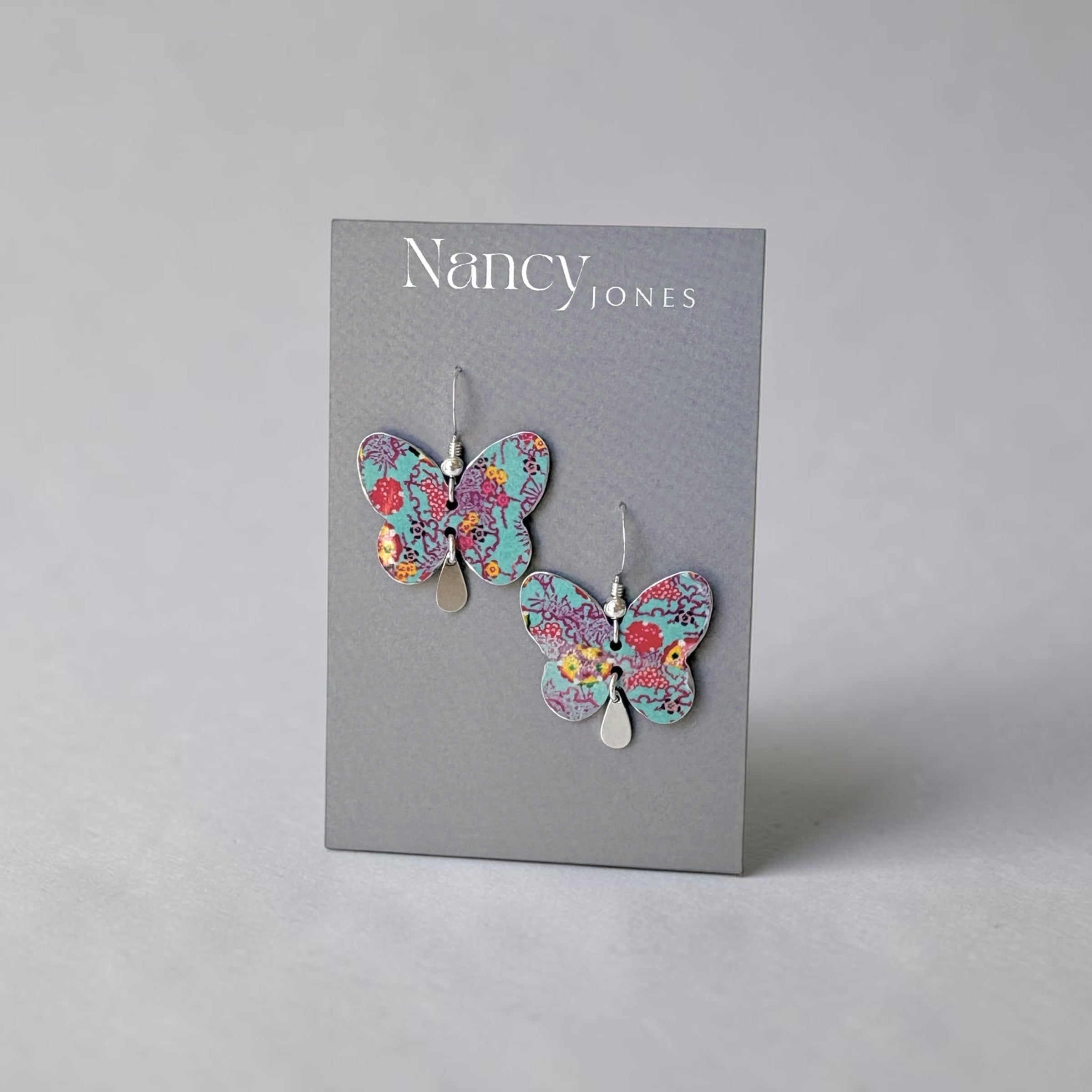 Butterfly earrings on a Nancy Jones branded card against a gray background