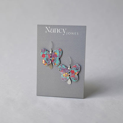 Butterfly earrings on a Nancy Jones branded card against a gray background