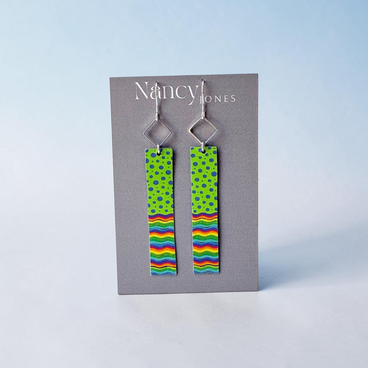 Pair of earrings with colorful patterns on a gray card with &