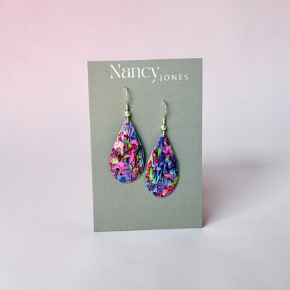 Colorful teardrop earrings on a Nancy Jones card against a light pink background