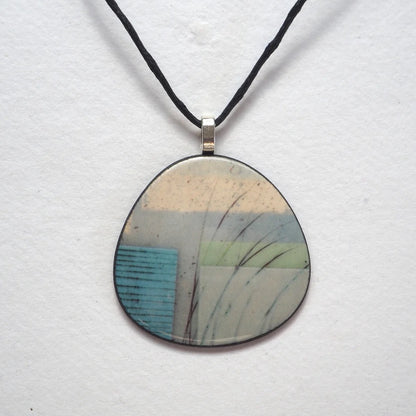Round pendant with nature-inspired design on a white background