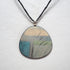 Round pendant with nature-inspired design on a white background
