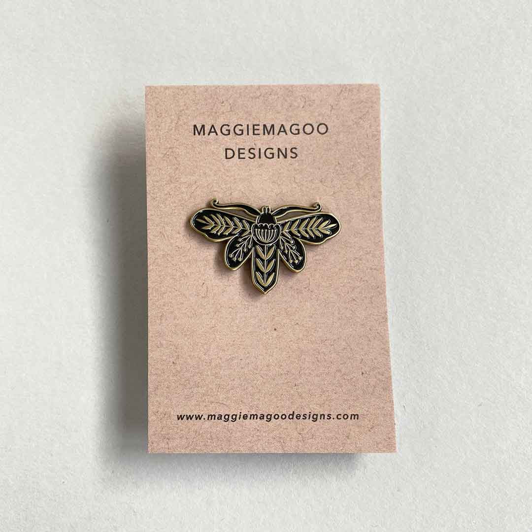 Insect-shaped pin on a beige card with &