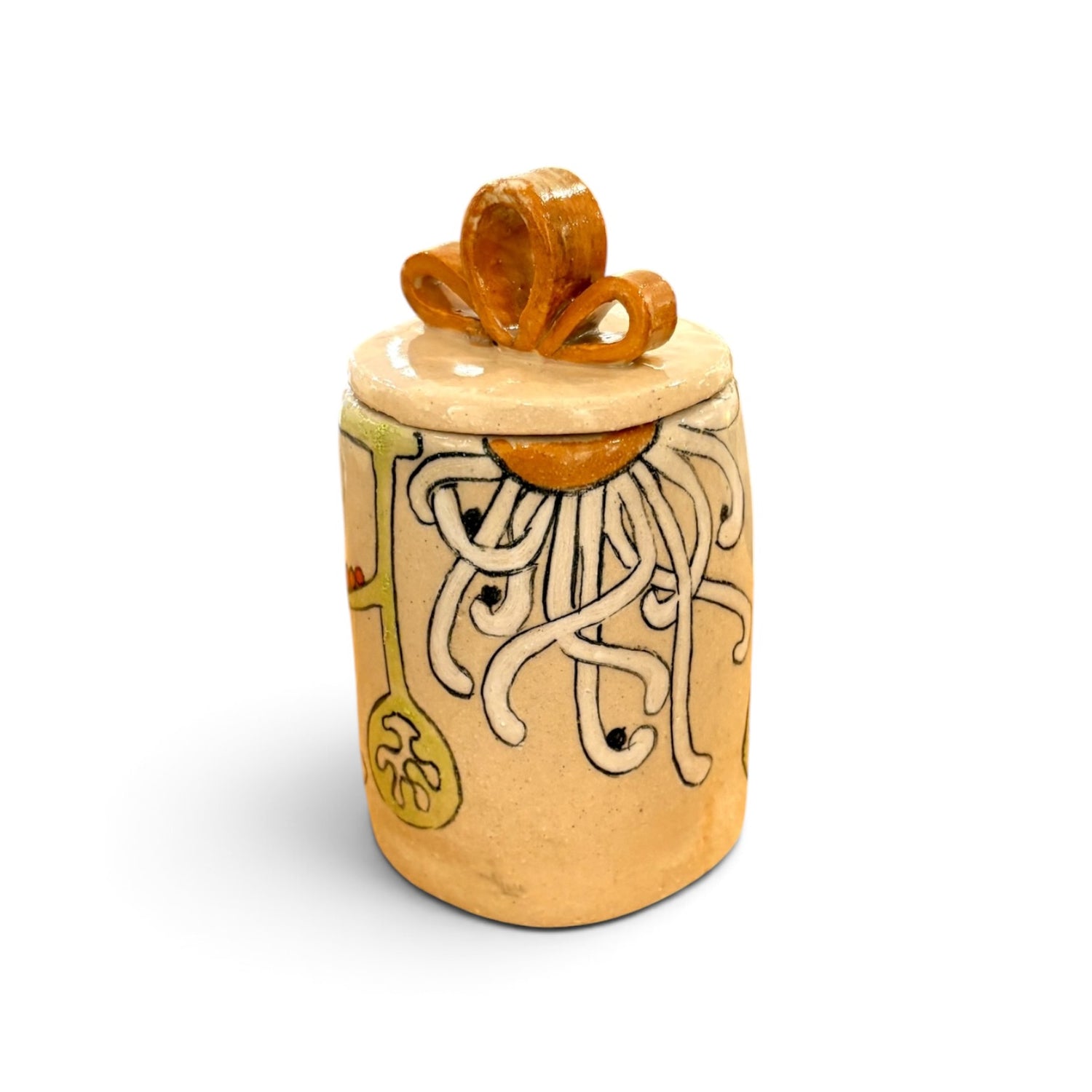 A handmade ceramic lidded jar with a beige body, hand-painted white tentacle-like pattern, yellow accents, and a glossy orange-brown lid ornament, shown on a white background.