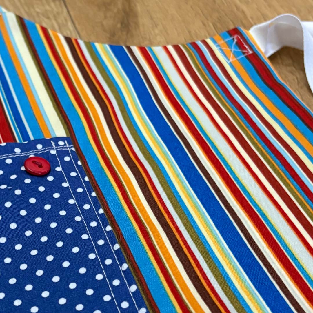 Colorful striped fabric with a blue polka dot pocket on a wooden surface_Just Makers