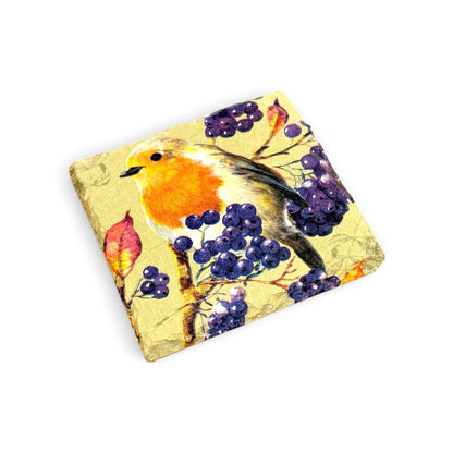 A square decorative coaster featuring a watercolor-style robin bird perched among purple grapes on a textured gold background, shown on a plain white studio background.
