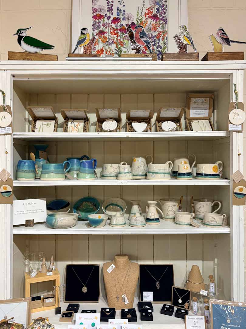 Display case with ceramic items, jewelry, and decorative birds on a shelf.