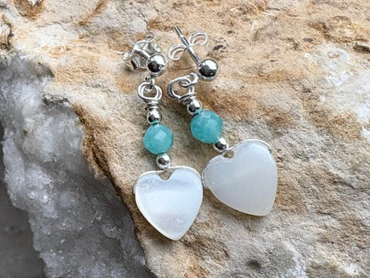 Heart-shaped earrings with turquoise beads on a stone background
