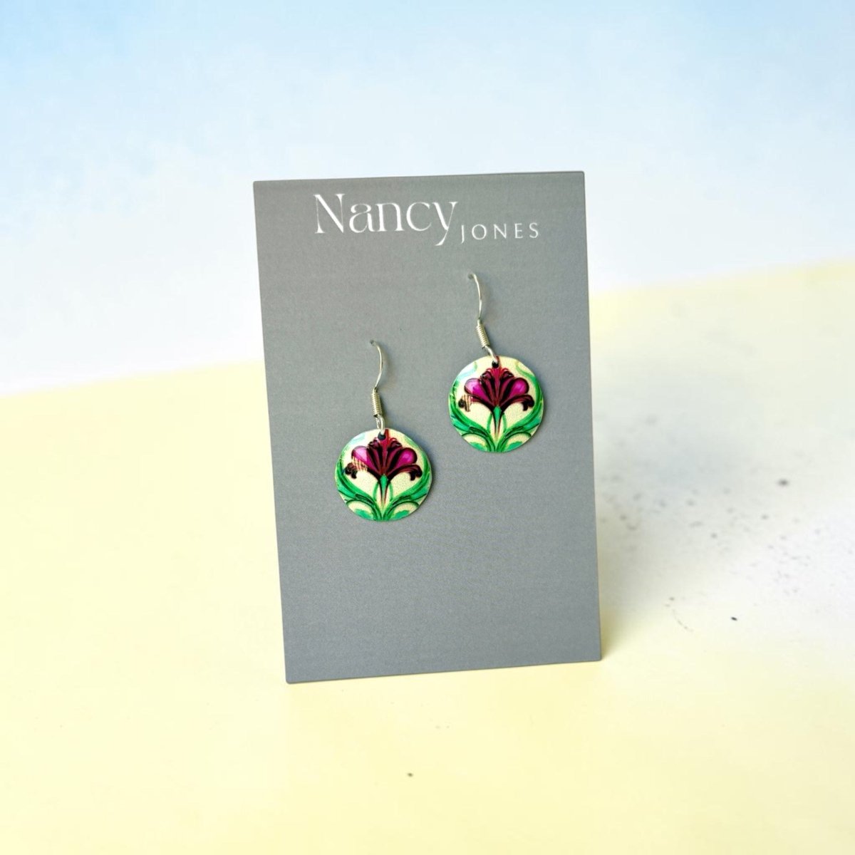Floral earrings on a Nancy Jones card against a light blue and beige background