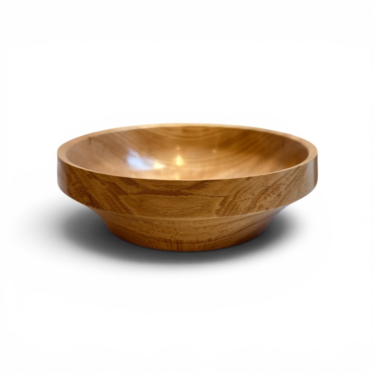 A round wooden bowl with a natural warm brown finish and visible wood grain, photographed on a clean white background with a soft shadow underneath.