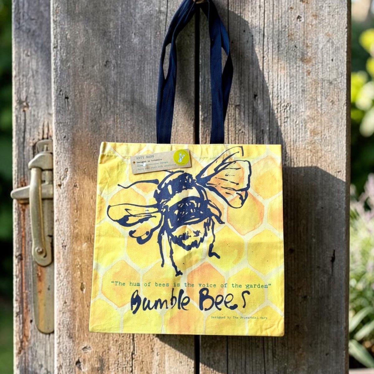 Yellow tote bag with bee design hanging on a wooden door