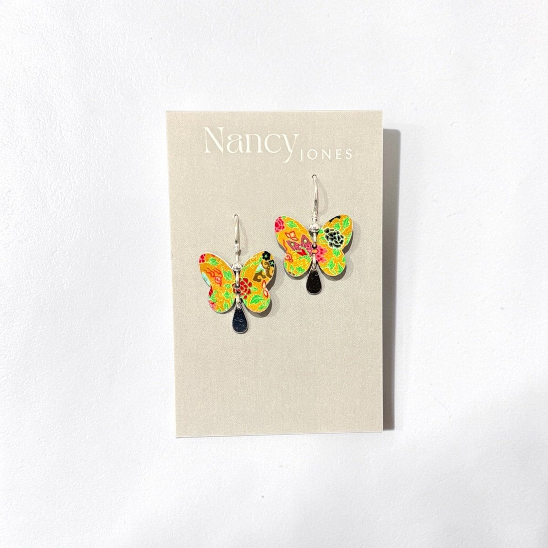 Butterfly earrings on a Nancy Jones branded card against a white background