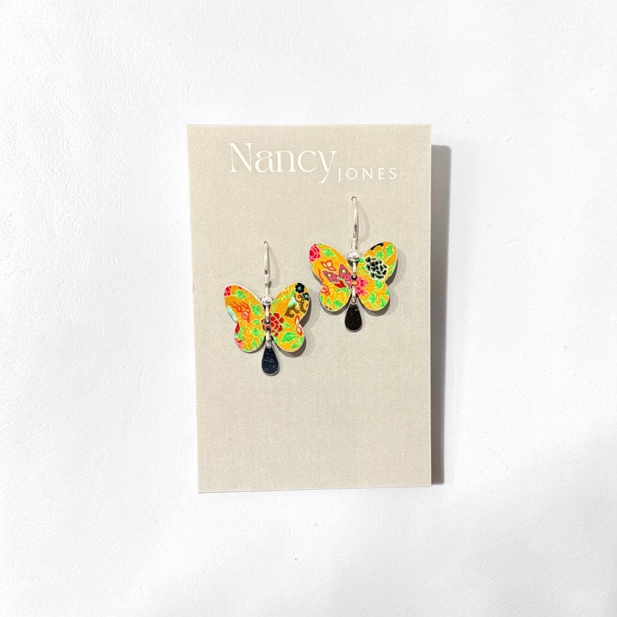 Butterfly earrings on a Nancy Jones branded card against a white background