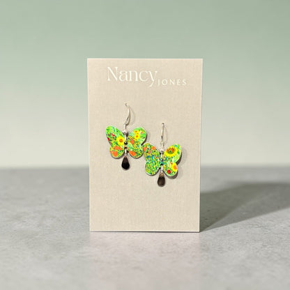 Butterfly-shaped earrings on a Nancy Jones card against a gray background