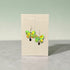 Butterfly-shaped earrings on a Nancy Jones card against a gray background