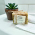 Calendula Petal Soap with a label on a white surface next to a potted plant.