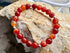 Red beaded bracelet with silver accents on a rock