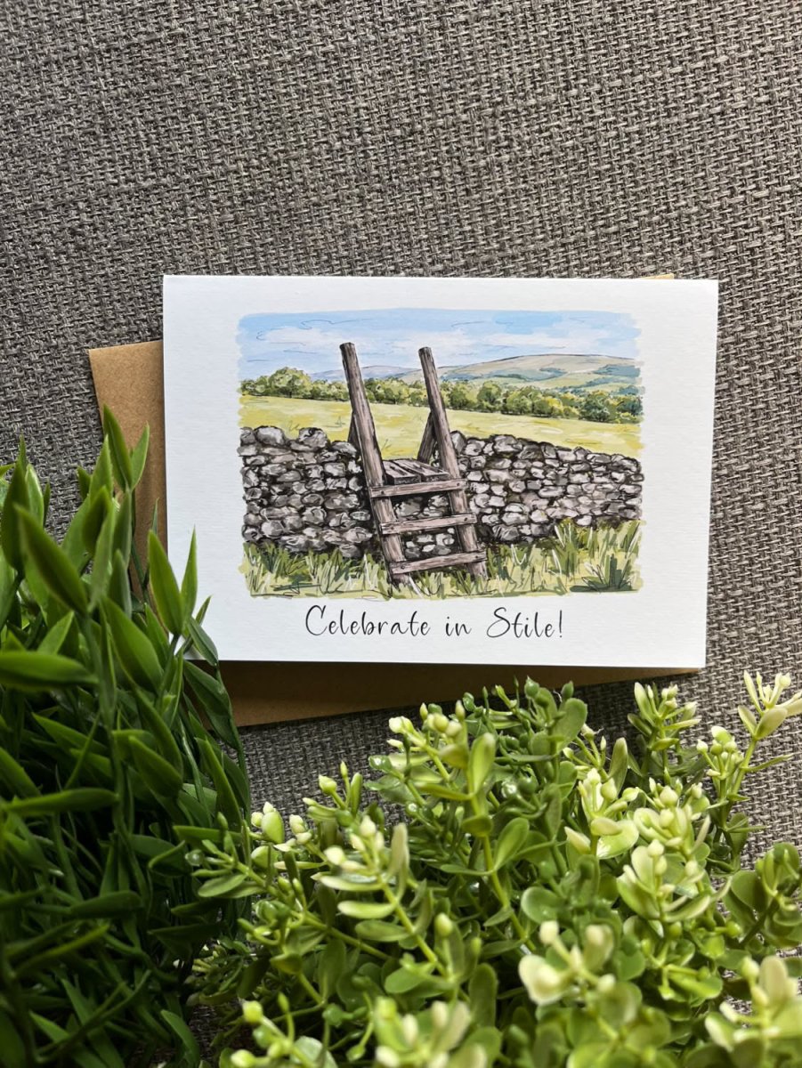 A square greeting card with a watercolor illustration of a stone wall and ladder in a countryside landscape, printed with the phrase &