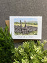 A square greeting card with a watercolor illustration of a stone wall and ladder in a countryside landscape, printed with the phrase &